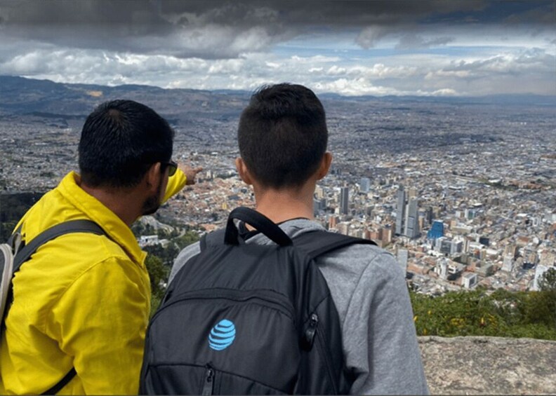 Two individuals overlooking a cityscape with a cloudy sky. 2