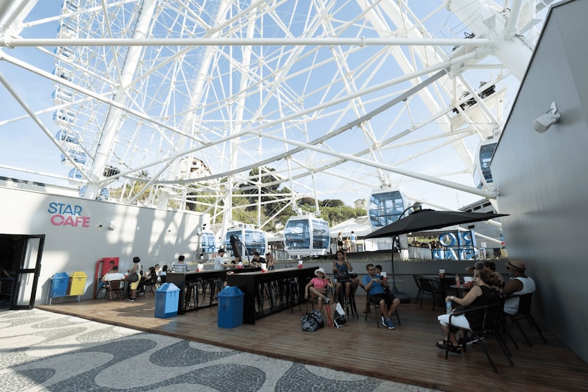 A Ferris wheel, outdoor seating area, and a Star Cafe on a cruise ship deck. 5