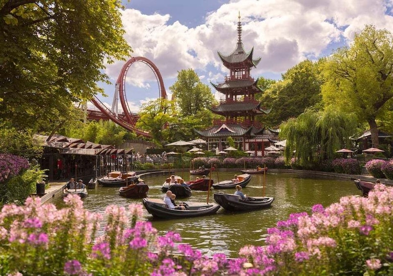 Un parque con una pagoda, una montaña rusa y barcos en el agua. 3