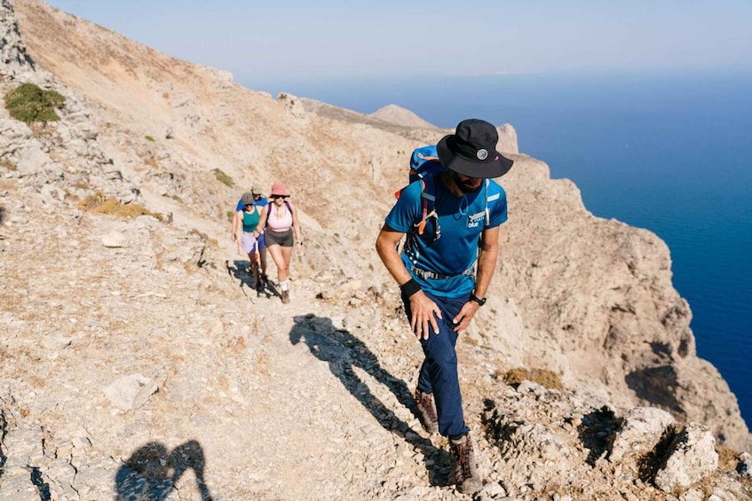 Un excursionista en un sendero rocoso con vista despejada al mar. 1