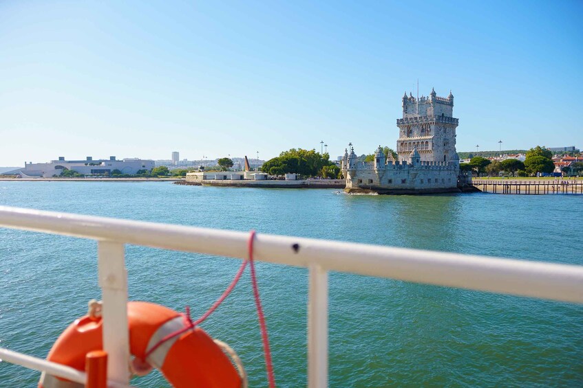 Una torre histórica junto a un río, con un edificio moderno al fondo. 3