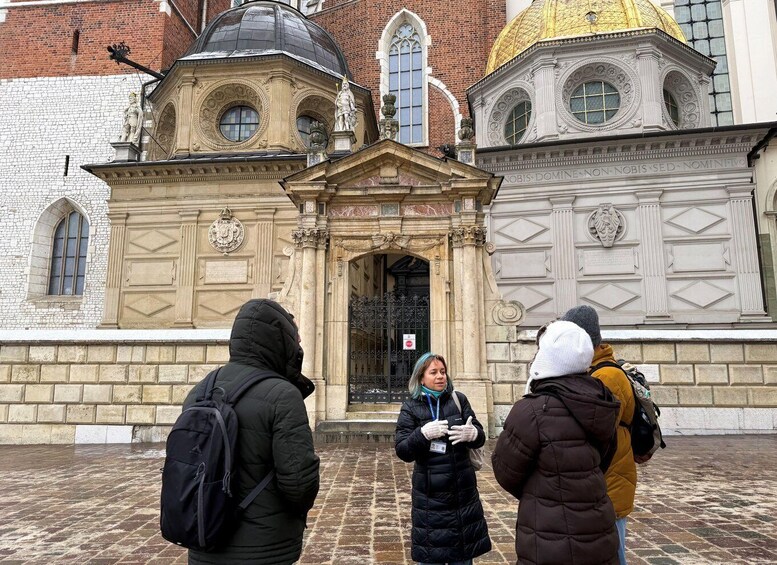 Tre personer står foran en historisk bygning med detaljeret arkitektur og en gylden kuppel. 5
