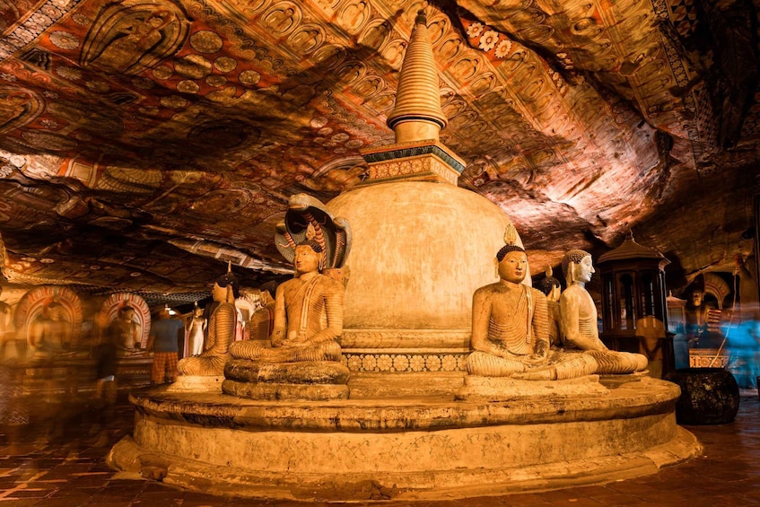 En stor Buddha-statue omgivet af mindre statuer i et tempel med detaljerede himmelkunstværker. 5