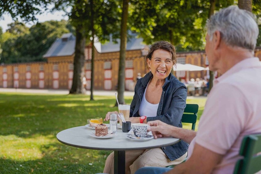 Two people sitting at a round table outdoors with food and drinks. 5