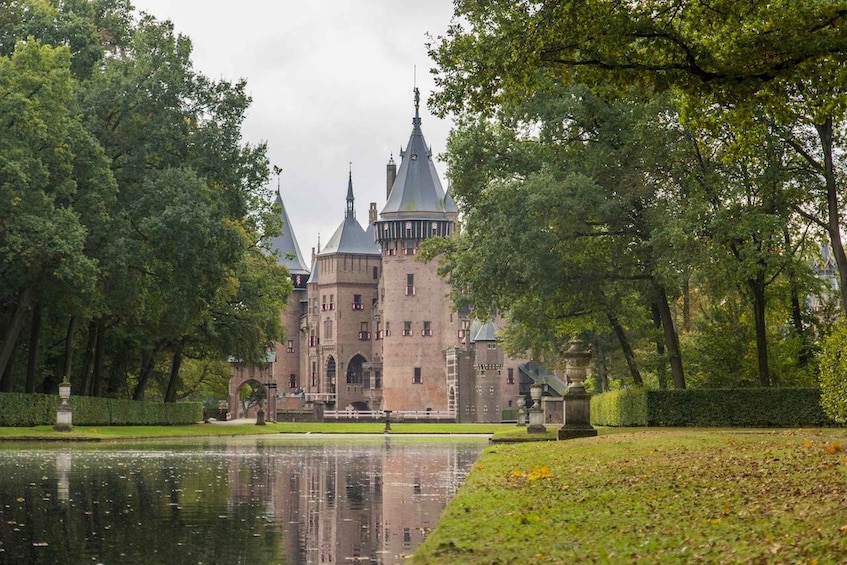 A historic castle with multiple spires, surrounded by a well-maintained garden and a reflective pond. 4