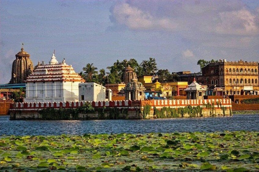 Un ensemble de temples situé au bord d’un plan d’eau dont les rives sont couvertes de lotus, présentant une architecture traditionnelle et surplombant un ciel dégagé. 3