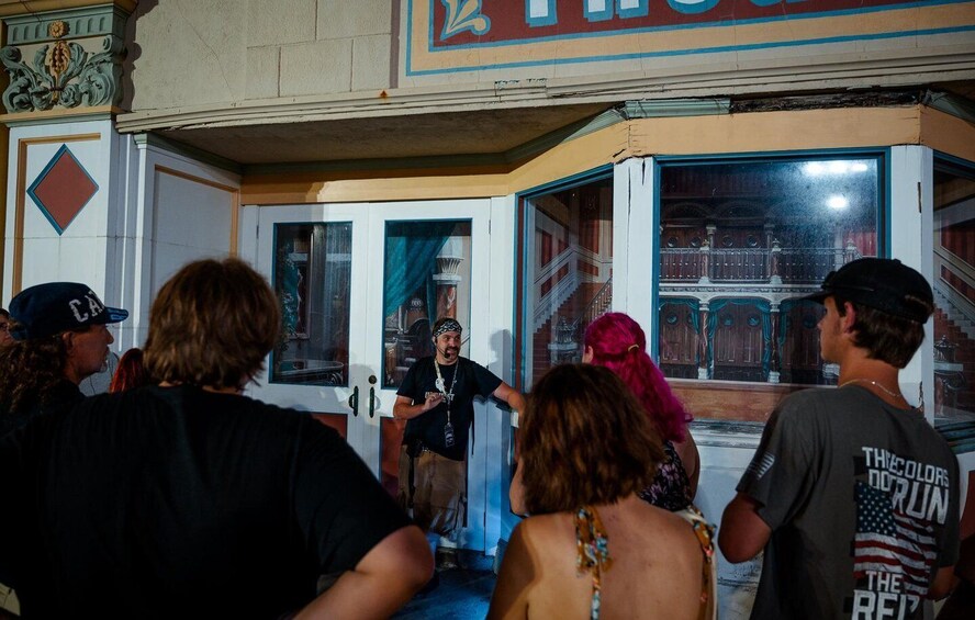 A group of people standing in front of a building with a large window and a door. 4