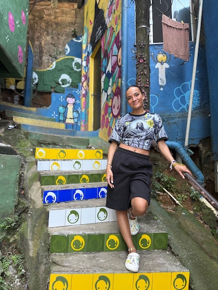 En person sidder på farverige trin foran en muralmaleri. 4