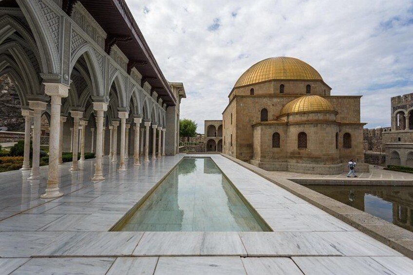 Un cortile con piscina, una grande cupola dorata e un edificio con archi. 5