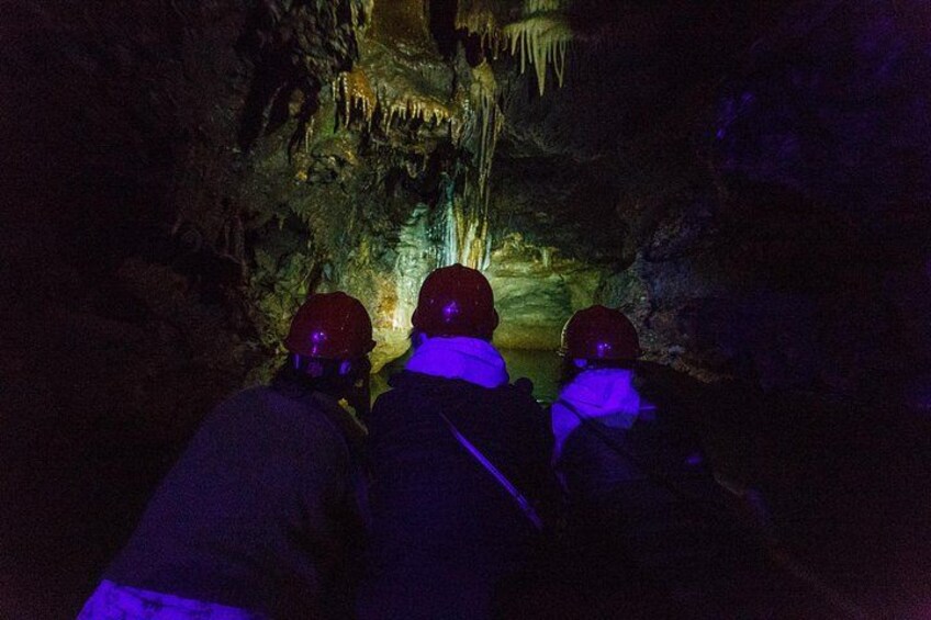 Tre persone con caschi e giacche all'interno di una grotta con stalattiti. 2
