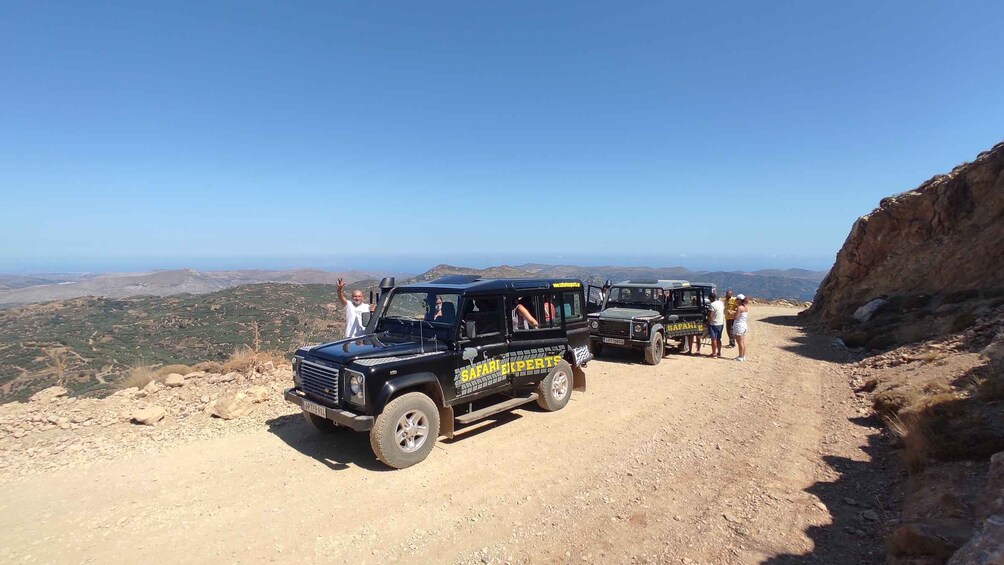 A safari vehicle on a dirt road with people around it. 4