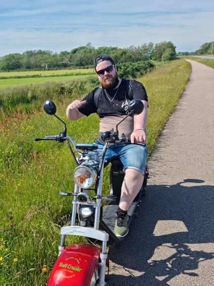 A person sitting on a motorcycle on a rural road with greenery on both sides. 3