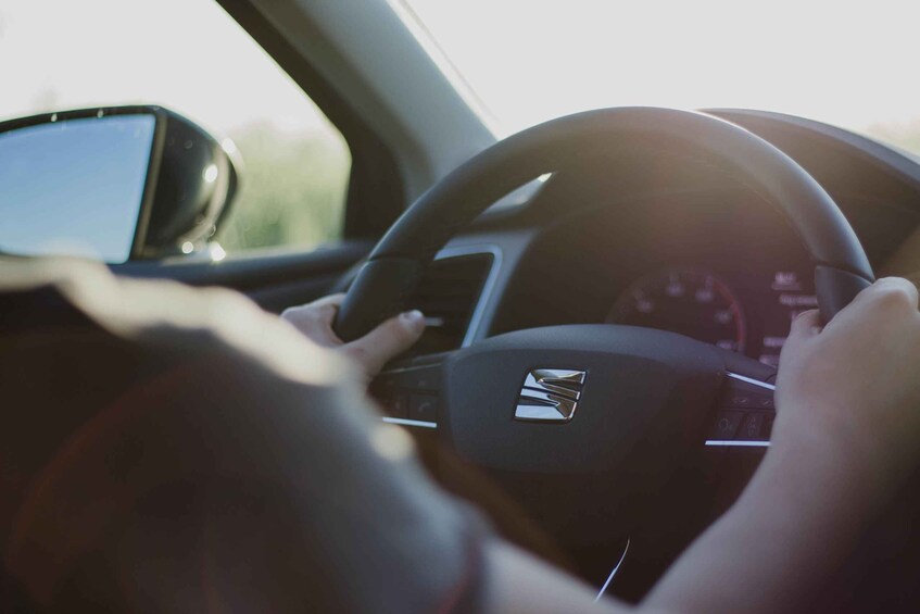 A person driving a car with a smartphone mounted on the dashboard. 3