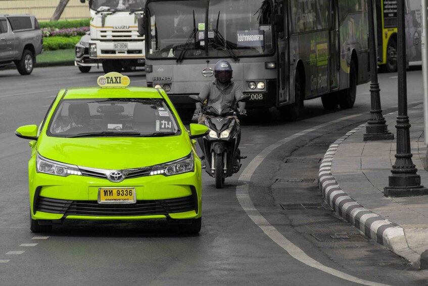 A bright green taxi with a sign, a motorcycle, and a bus on a city street. 4