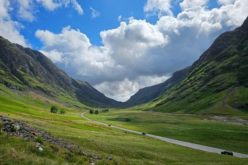 A winding road through a valley with mountains on either side. 3