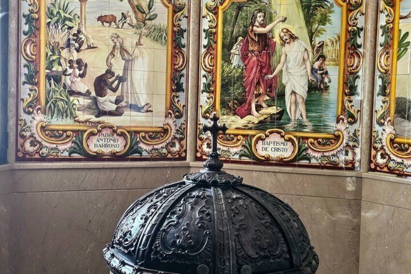A tiled wall with religious scenes and a black ornate structure. 3
