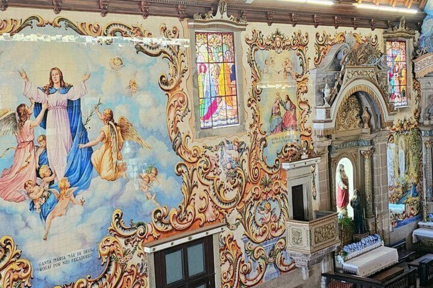 An ornate church interior with elaborate frescoes, stained glass windows, and a statue of the Virgin Mary. 2