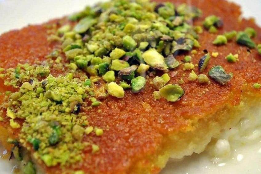 A dessert with a golden-brown crust, topped with chopped green pistachios. 4