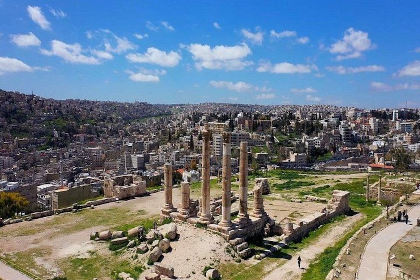 Ancient ruins with columns, a paved path, and a cityscape in the background. 3