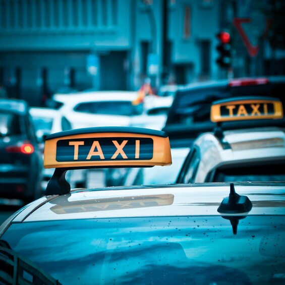 Een taxi met een 'TAXI'-bord op het dak, omringd door andere voertuigen op een stadsgestraat. 4