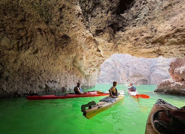 People kayaking in a cave with clear water and rocky walls. 5
