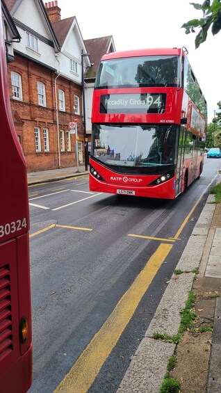 Ein roter Doppeldeckerbus mit der Aufschrift 'Piccadilly Circus' auf einer Stadtstraße. 1