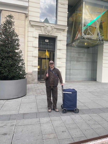 Eine Person steht auf einem befestigten Weg mit einem Koffer und einer Wanderungshilfe. 2