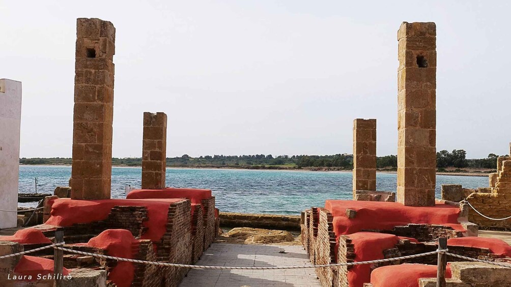 Antiche colonne in pietra e mura vicino a un corpo d'acqua. 4