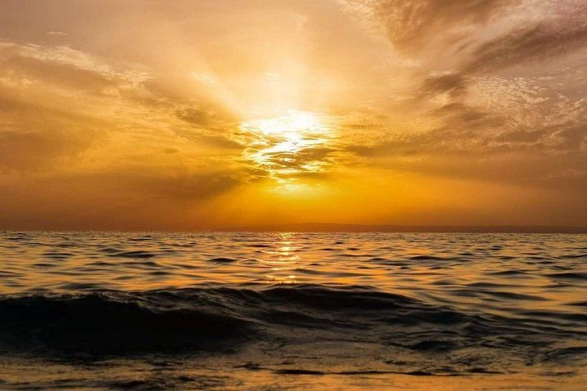 A sunset over the ocean with waves and a cloudy sky. 3