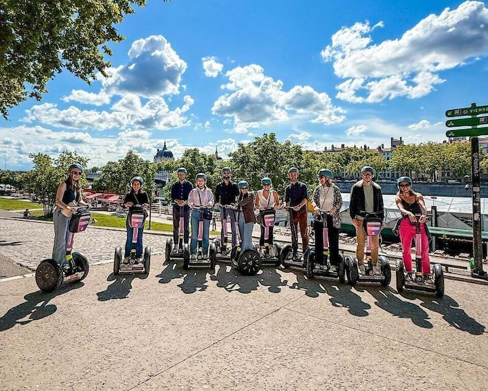 A group of people on segways in a park with a clear sky and a distant building. 2