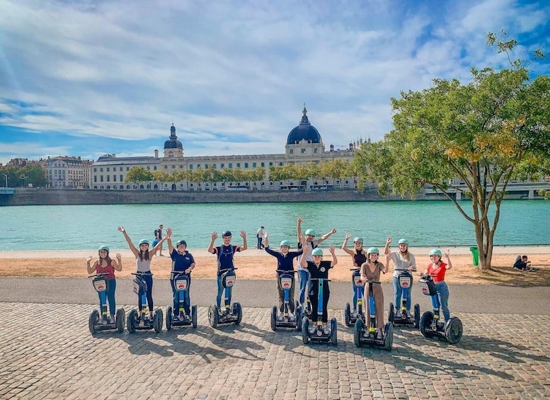 A group of people on Segway hoverboards by a river with a historic building in the background. 3