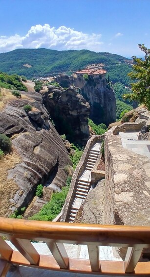 Una escalera de piedra que conduce a un acantilado con vistas a un valle y un edificio de techo rojo. 5
