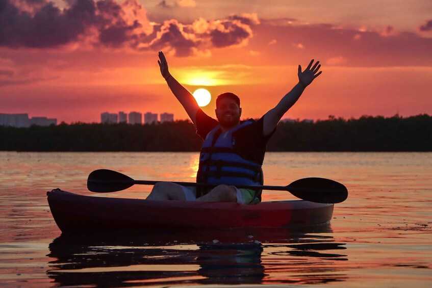 A person kayaking with arms raised against a sunset backdrop. 4