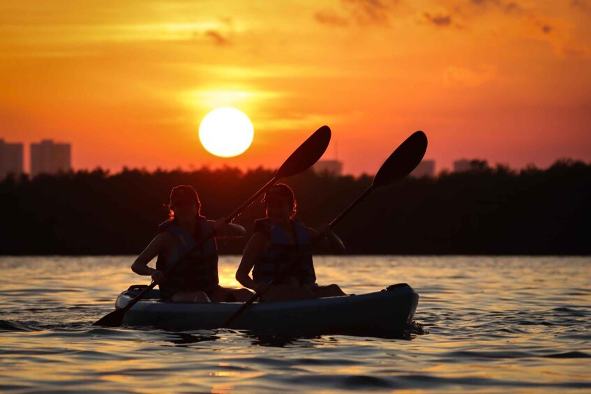 Two people kayaking on a body of water during sunset. 5