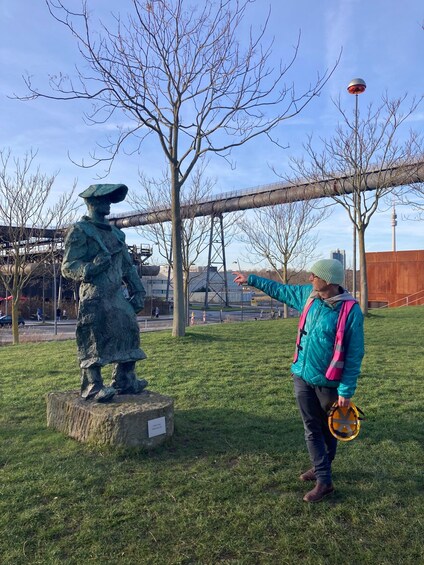 A person interacting with a statue in a park with a bridge and buildings in the background. 4