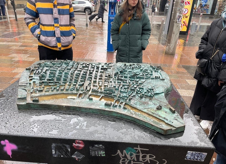 A detailed model of a cityscape on display, surrounded by wet pavement and graffiti. 5