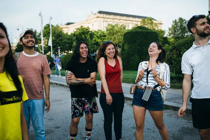 A group of people standing on a street with a large building in the background. 3