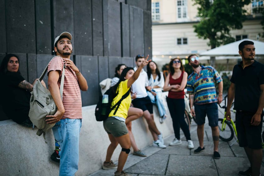 A group of people standing and sitting on a city sidewalk. 2