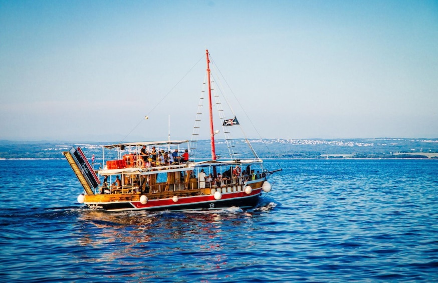 A boat with passengers on a calm sea, a clear sky, and distant land. 1