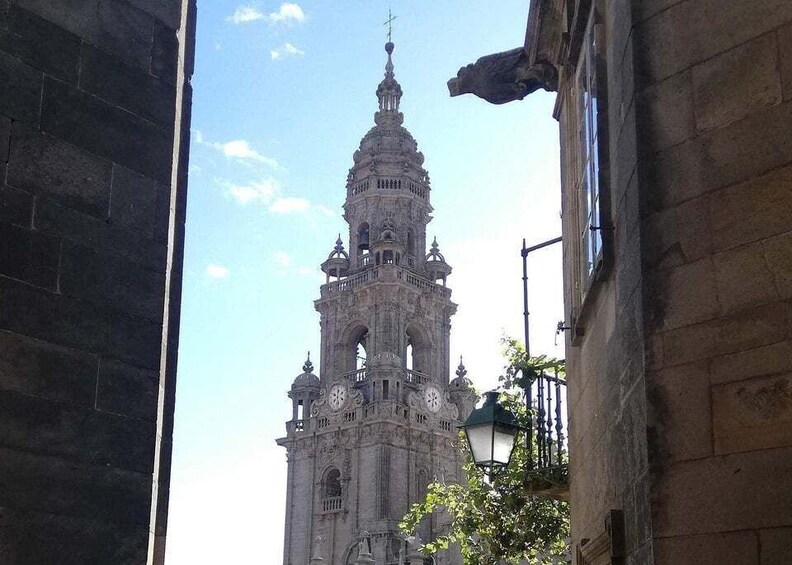 A historic tower with intricate architecture and a clock, viewed through a narrow street. 5