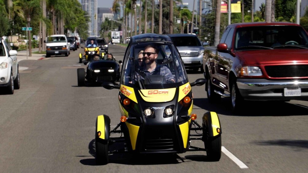 A GoCar driving on a city street with palm trees and buildings in the background. 5