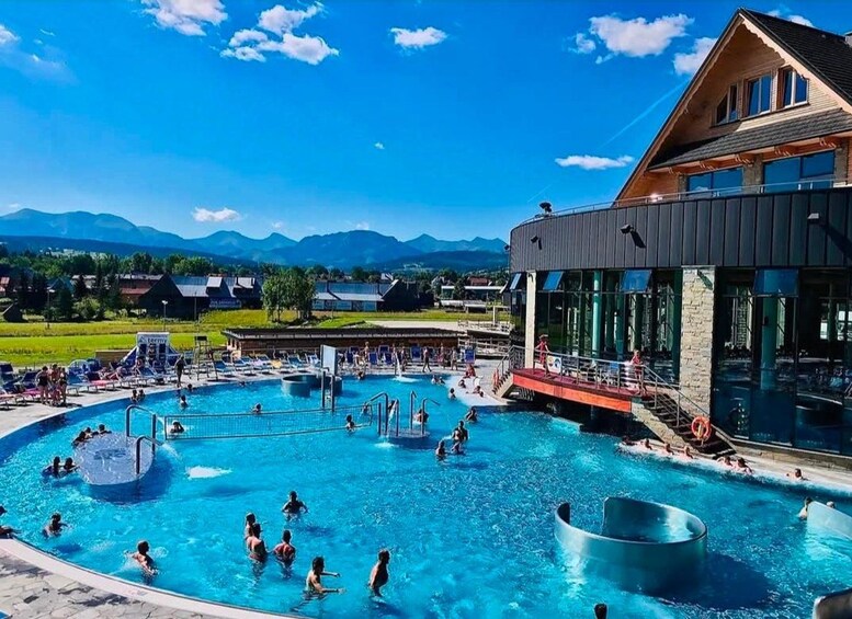 Une piscine où se baignent des gens, un bâtiment doté de grandes fenêtres et, au loin, des montagnes. 3