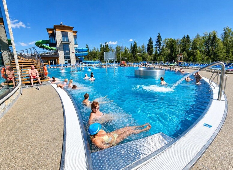 Une piscine avec des personnes à l’intérieur, un toboggan aquatique et un bâtiment en arrière-plan. 2