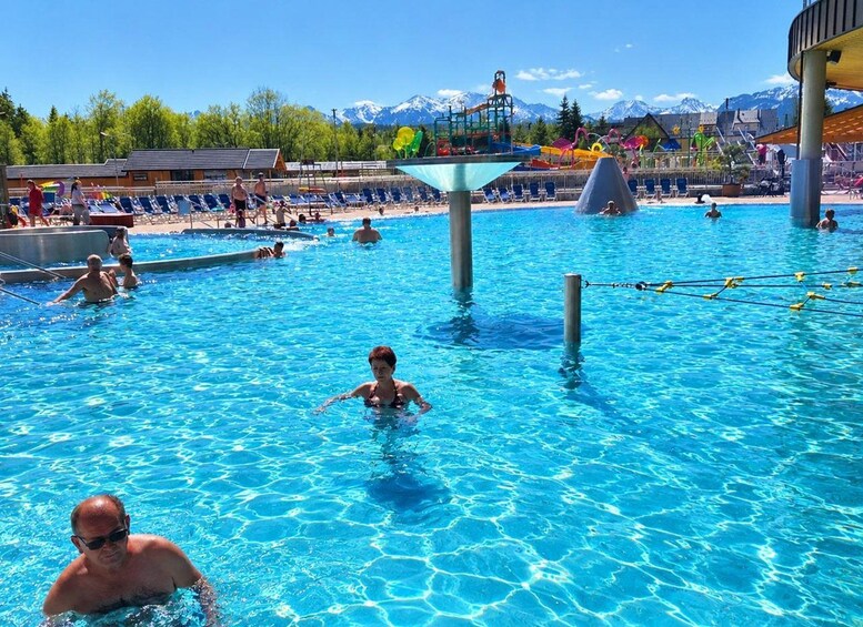 Une piscine avec des gens, un toboggan aquatique et des montagnes en arrière-plan. 4