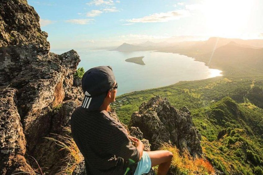 Una persona sentada en un acantilado con vistas a un lago y montañas al fondo. 1