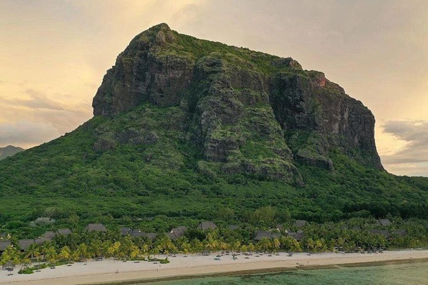 Una gran montaña verde con una playa en primer plano. 2