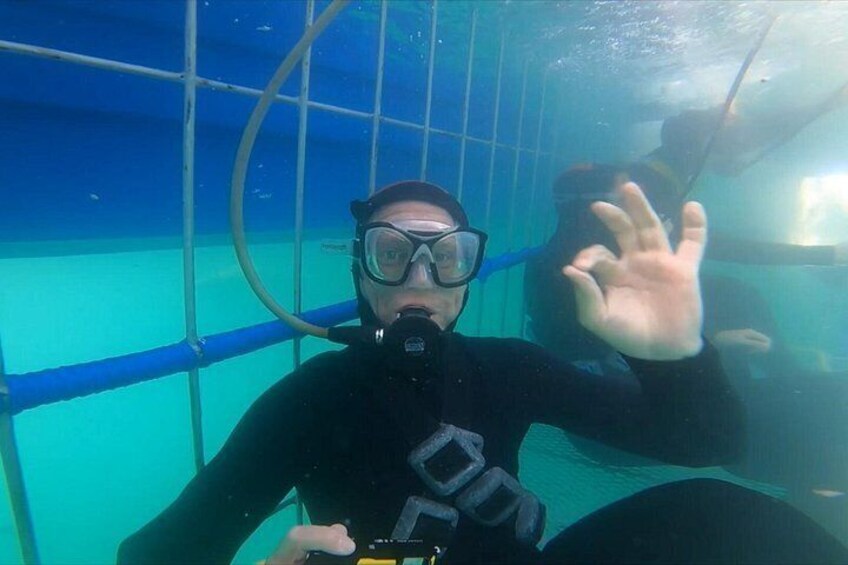 Une personne se trouve sous l’eau, dans une piscine bleue bordée de barres métalliques, vêtue d’une combinaison de plongée noire et équipée de matériel de plongée. 4