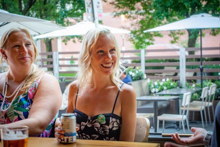 Zwei Personen sitzen an einem Tisch im Freien mit einer Bierdose und einem Glas. 4