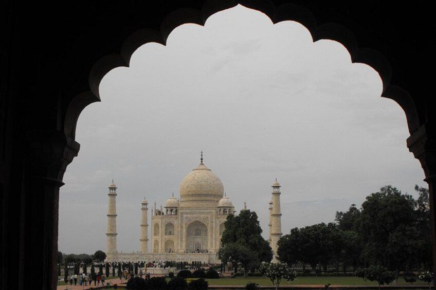 The Taj Mahal with four minarets, surrounded by trees and a crowd of people. 3