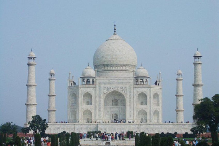 The Taj Mahal with four minarets, a large central dome, and a crowd of people in the foreground. 4